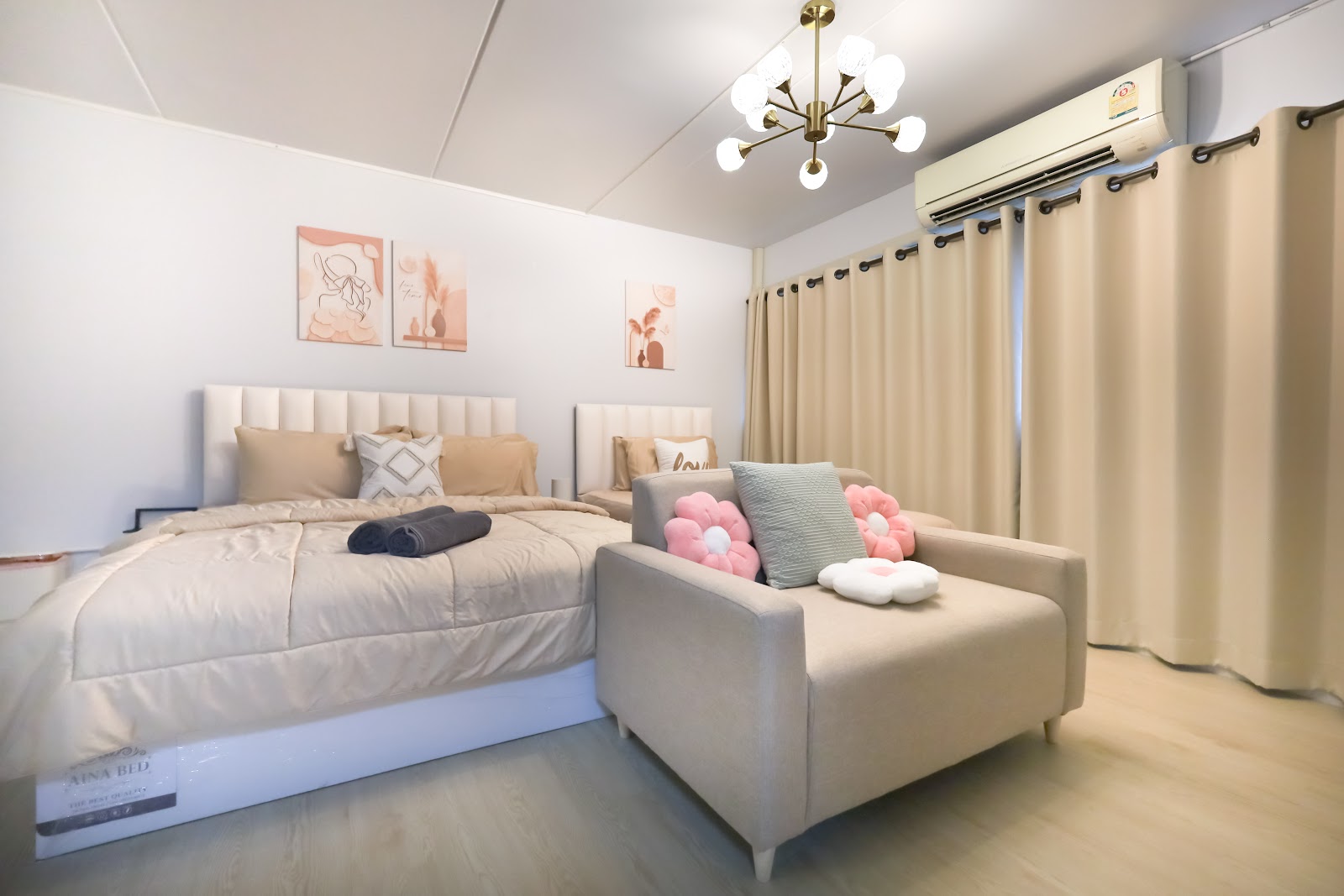 A softly styled MC Travelers studio — cream beds, gold chandelier, pink flower cushions